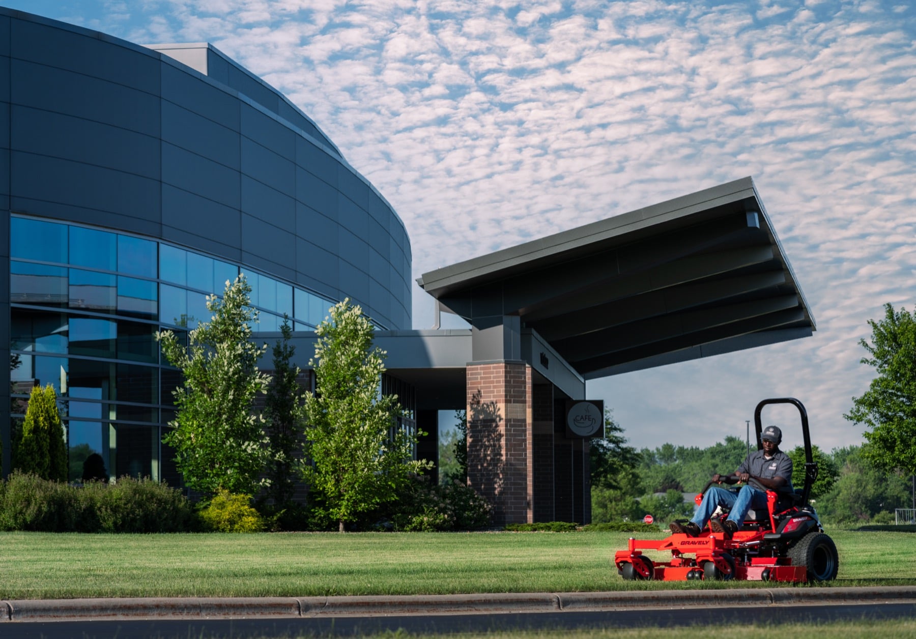 An operator on a Gravely zero-turn mower cutting the lawn of a commercial property